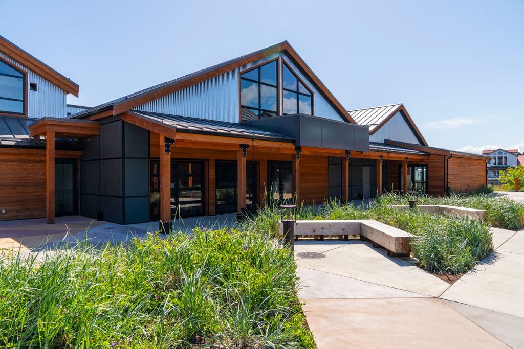 Modern building with wood and metal siding, large windows, and a landscaped garden walkway.